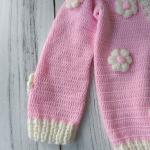 Hand-knitted, pink, floral patterned girl's cardigan.