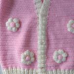 Hand-knitted, pink, floral patterned girl's cardigan.