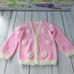 Hand-knitted, pink, floral patterned girl's cardigan.