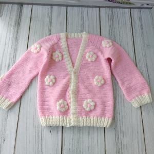 Hand-knitted, pink, floral patterned girl's cardigan.