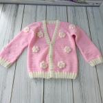 Hand-knitted, pink, floral patterned girl's cardigan.
