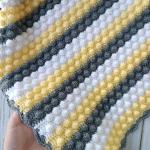 Hand-knitted baby blanket - embossed pattern in yellow, white and anthracite colors.